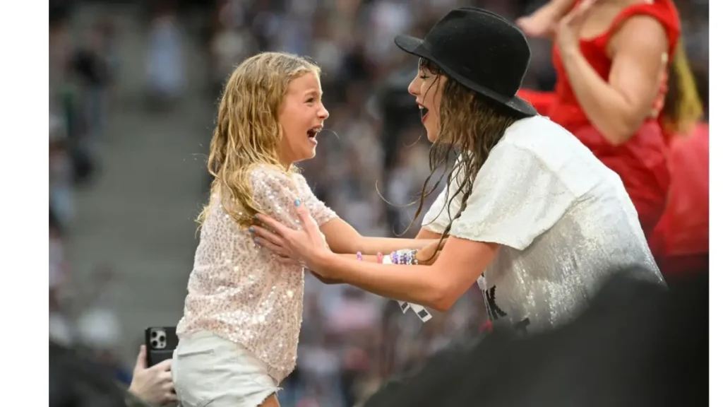 Taylor Swift joyfully interacting with a young girl in the audience.