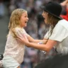 Taylor Swift joyfully interacting with a young girl in the audience.